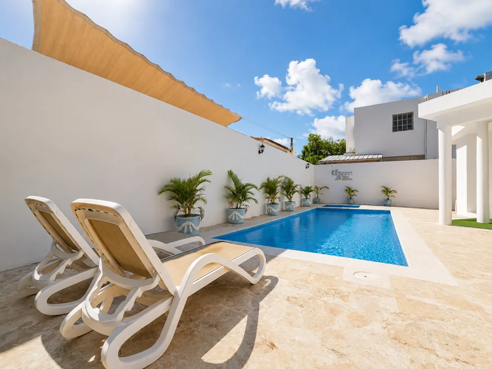 Sun loungers on the pool terrace, under the shade sail